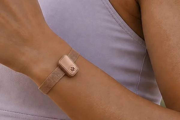 Wrist-worn smartwatch with rose gold finish and mesh band on person wearing lavender clothing.