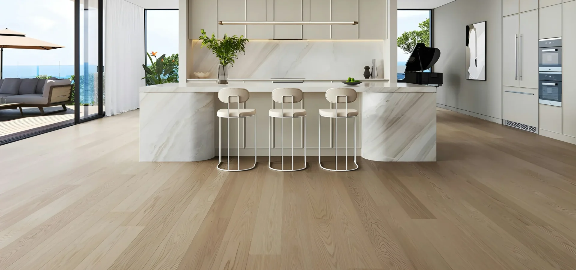 Modern luxury kitchen with marble island, three bar stools, white cabinetry, and expansive windows overlooking ocean views.